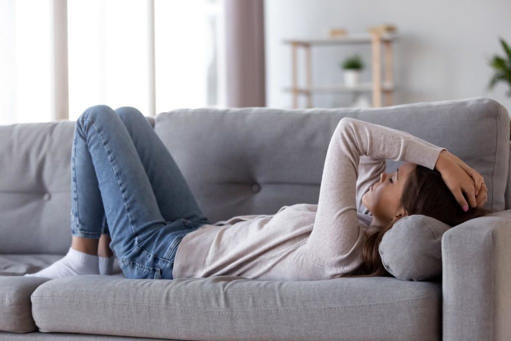 Woman lying on the couch in pain from fibromyalgia symptoms